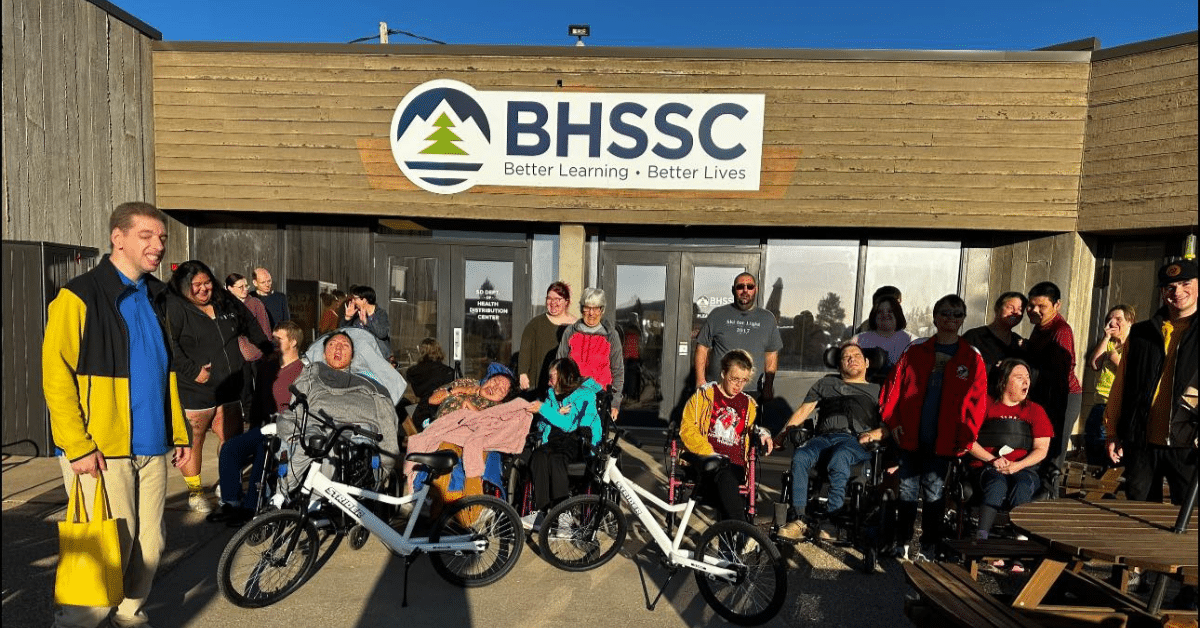 People stand in front of BHSSC Pleasant Valley building with two bikes donated by Strider.